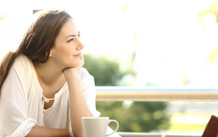 Relaxed and dreaming woman with cup of coffee
